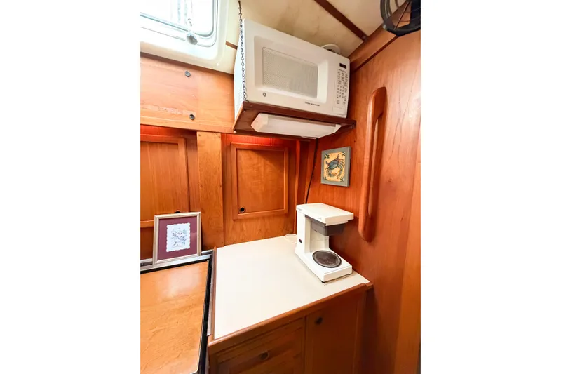 Slide: The Image of 1986 Nauticat 40 yacht interior with microwave, coffee maker, and wooden cabinetry. - 76