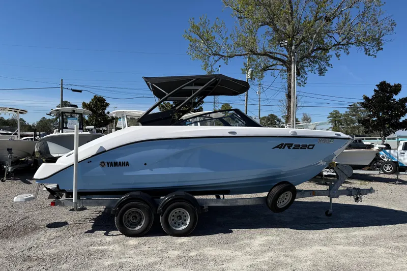 Slide: The Image of 2024 Yamaha Boats AR220 on trailer, displayed outdoors under clear blue sky. - 13