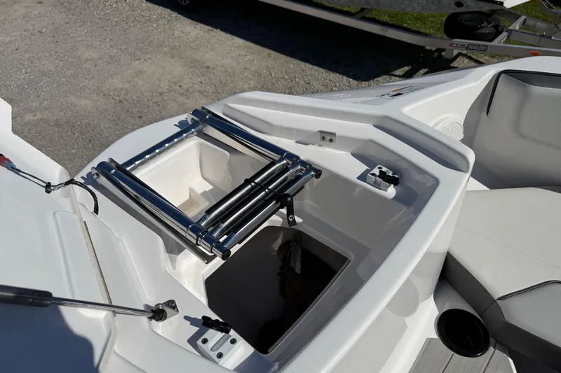 Slide: The Image of 2024 Yamaha Boats AR220 bow storage with stainless steel ladder and seating area. - 22