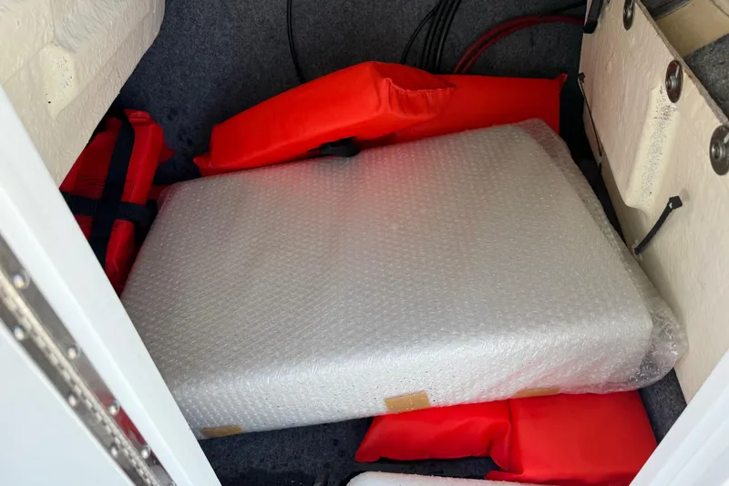 Slide: The Image of Storage compartment in 2024 Yamaha AR220 boat with life jackets and bubble-wrapped item. - 25