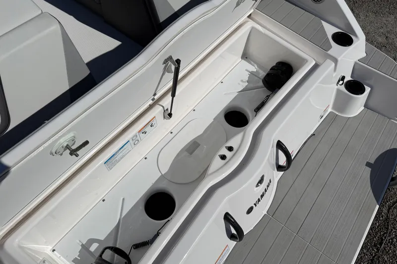 Slide: The Image of 2024 Yamaha Boats AR220 storage compartment with cup holders and seating area. - 36