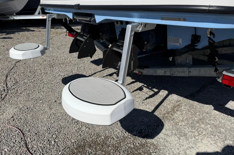 Slide: The Image of 2024 Yamaha Boats AR220 rear view with swim platforms on gravel surface. - 8