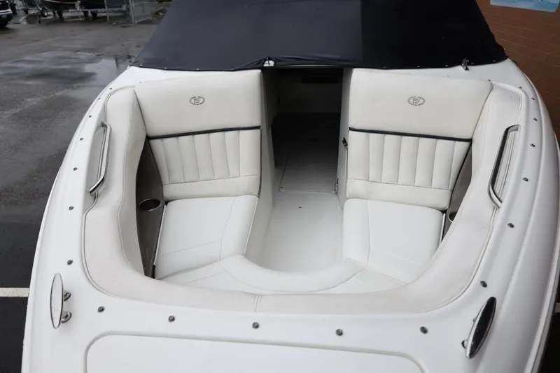 Slide: The Image of 2005 Cobalt 200 boat interior with white cushioned seating and black cover. - 38