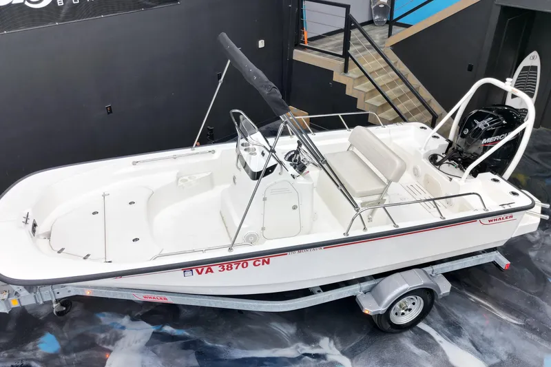 Slide: The Image of 2025 Boston Whaler 170 Montauk boat on trailer, displayed indoors. - 13
