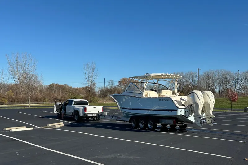Slide: The Image of 2024 Grady-White Freedom 307 boat on trailer, parked with truck in empty lot. - 7