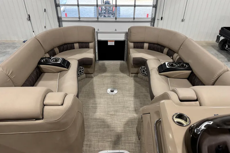 Slide: The Image of 2019 Bennington R23 pontoon boat interior with beige seating and cup holders in a garage. - 8