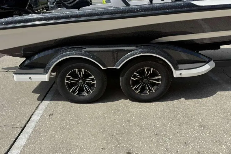 Slide: The Image of 2025 Caymas CX 20 PRO boat trailer with dual black alloy wheels on pavement. - 16