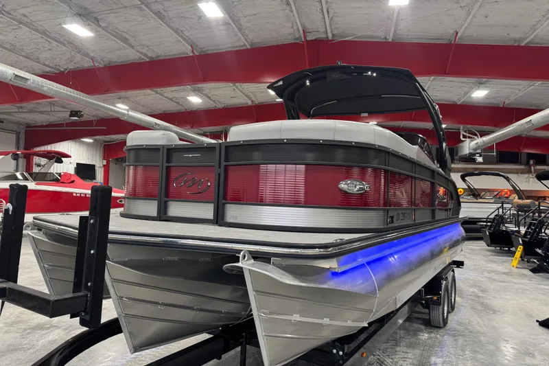 Slide: The Image of 2021 Manitou 25 LX pontoon boat in showroom with red and silver design. - 5