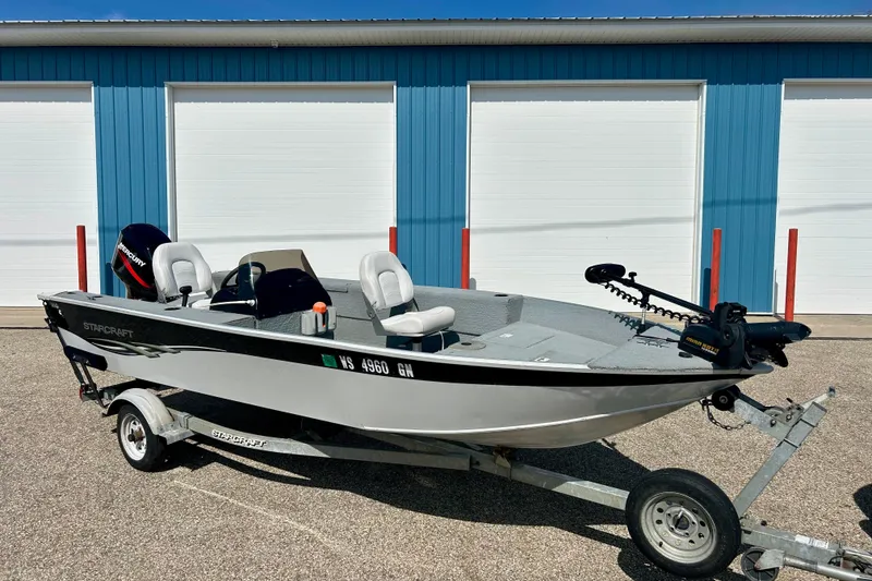 Slide: The Image of 2004 Starcraft D-Star 160 DLX SC boat on trailer, parked outside blue building. - 3