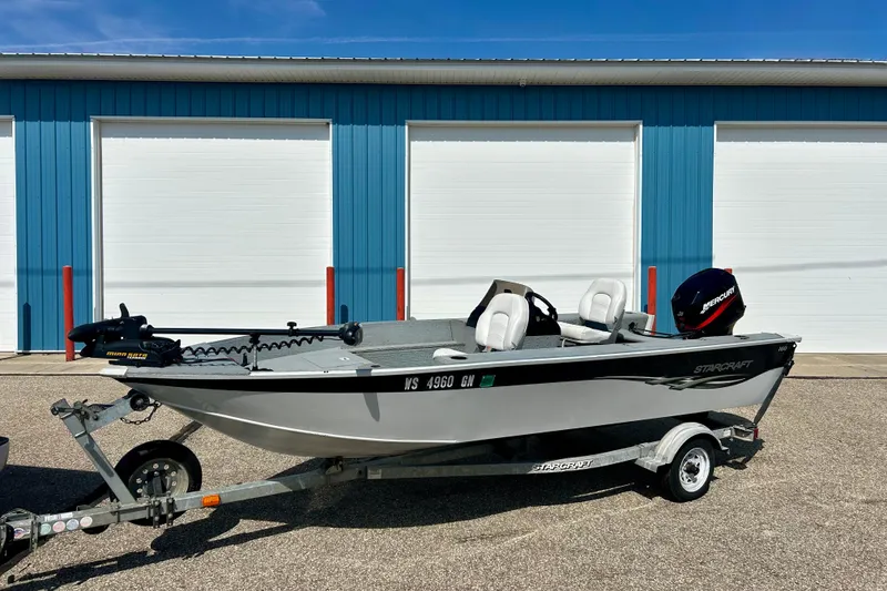 Slide: The Image of 2004 Starcraft D-Star 160 DLX SC boat on trailer, parked near blue storage units. - 33