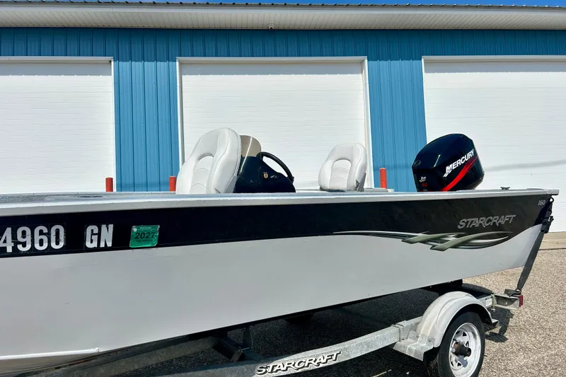 Slide: The Image of 2004 Starcraft D-Star 160 DLX SC boat with Mercury engine on trailer, parked by blue building. - 34