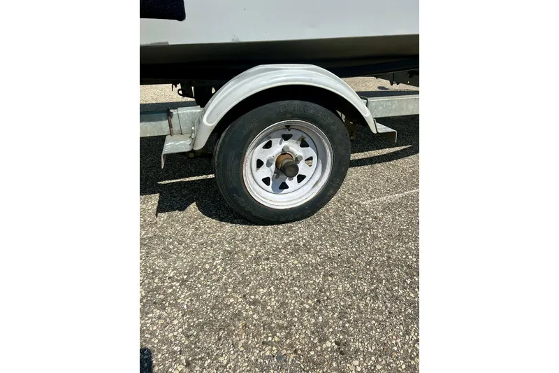 Slide: The Image of Trailer wheel of 2004 Starcraft D-Star 160 DLX SC on asphalt surface. - 36