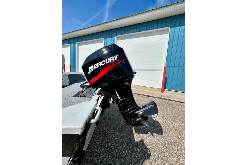 Slide: The Image of 2004 Starcraft D-Star 160 DLX SC boat with Mercury outboard motor, parked near blue garage. - 38