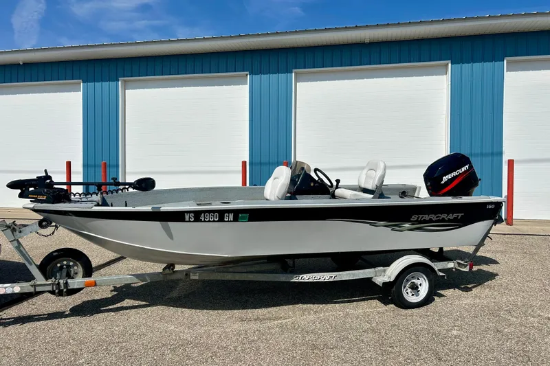 Slide: The Image of 2004 Starcraft D-Star 160 DLX SC boat on trailer, parked by blue building. - 4