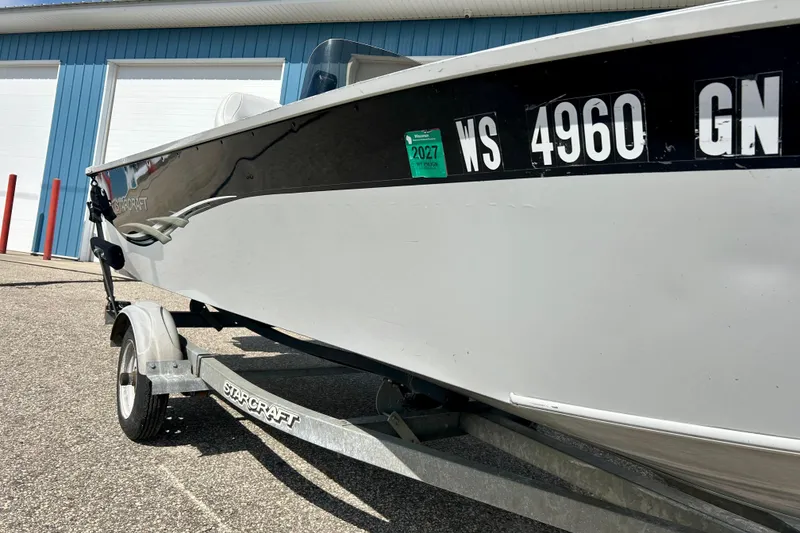 Slide: The Image of 2004 Starcraft D-Star 160 DLX SC boat on trailer, parked near blue building. - 5