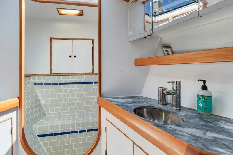 Slide: The Image of 1987 Macintosh Center Cockpit yacht bathroom with marble sink, tiled shower, and wooden accents. - 28