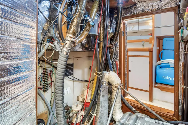 Slide: The Image of Engine room of a 1987 Macintosh Center Cockpit sailboat, showcasing complex wiring and equipment. - 34
