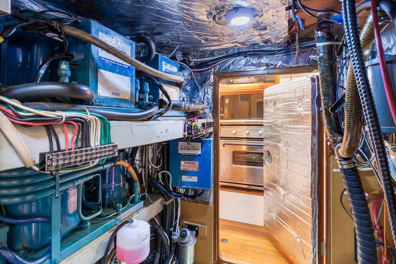 Slide: The Image of Engine room of a 1987 Macintosh Center Cockpit yacht with visible wiring and machinery. - 35