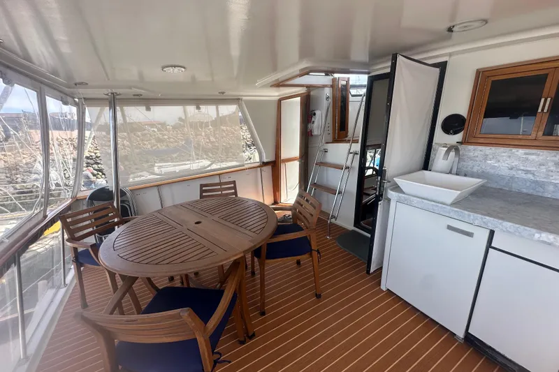 Slide: The Image of 1991 Californian 52 Cockpit Motor Yacht interior with wooden table, chairs, and kitchenette. - 16