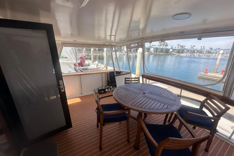 Slide: The Image of 1991 Californian 52 Cockpit Motor Yacht interior with wooden table and chairs, marina view. - 18