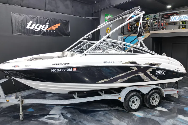 Slide: The Image of 2008 Yamaha Boats 212X on trailer, displayed indoors with Tige Boats banner. - 11