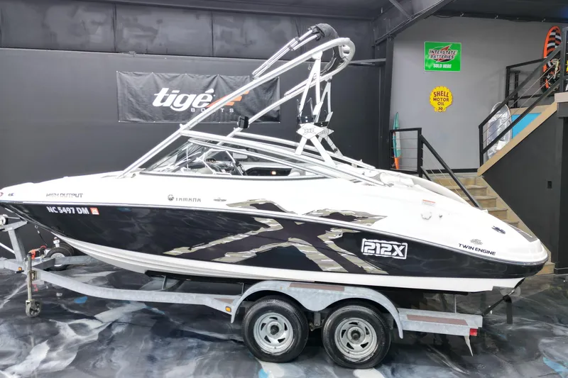 Slide: The Image of 2008 Yamaha Boats 212X on trailer in showroom, featuring sleek black and white design. - 2