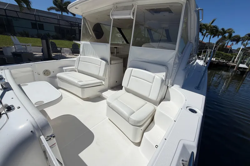 Slide: The Image of 2005 Tiara Yachts 3600 Sovran cockpit with white seating and table, docked by palm trees. - 12