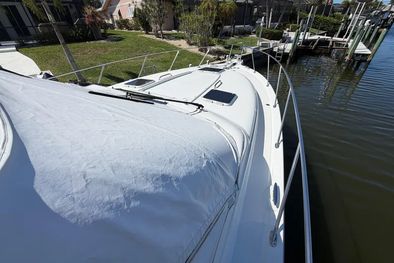 Slide: The Image of 2005 Tiara Yachts 3600 Sovran docked by a canal, showcasing sleek design and covered deck. - 5