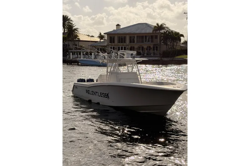Slide: The Image of 2017 Invincible 39 Open Fisherman boat named "Relentless" on water near a waterfront house. - 2