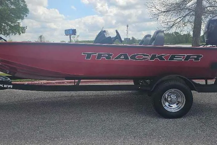 The Image of 2026 Tracker Pro Team 195 boat on trailer, red exterior, parked outdoors under cloudy sky. - 0