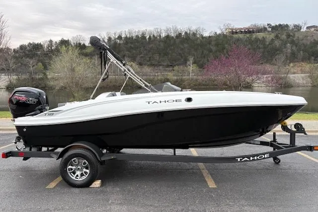 Slide: The Image of 2026 Tahoe T18 boat on trailer, parked outdoors near a scenic lake. - 62