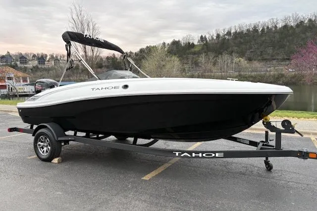 Slide: The Image of 2026 Tahoe T18 boat on trailer, parked near a scenic lake with trees in the background. - 64