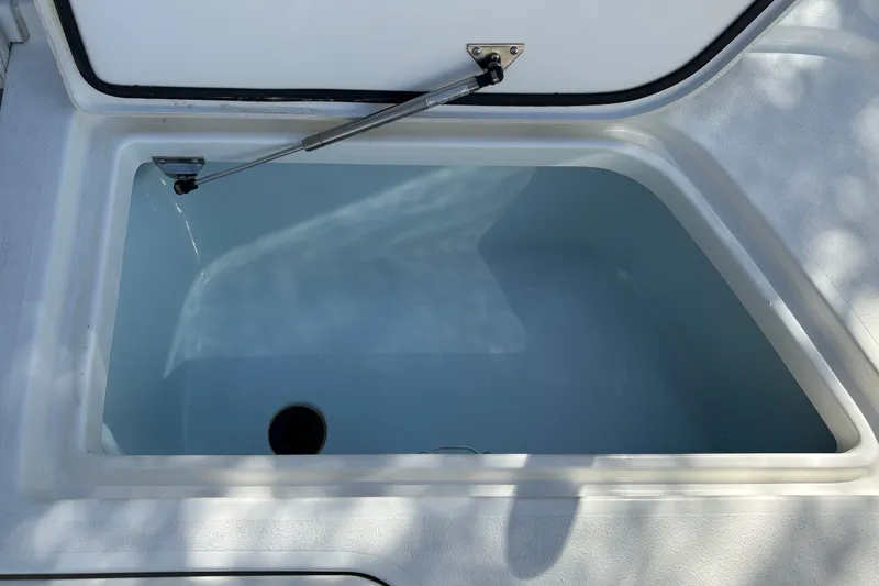 Slide: The Image of Open storage compartment on 2026 Mako 24 APEX boat, featuring a hydraulic lift. - 38