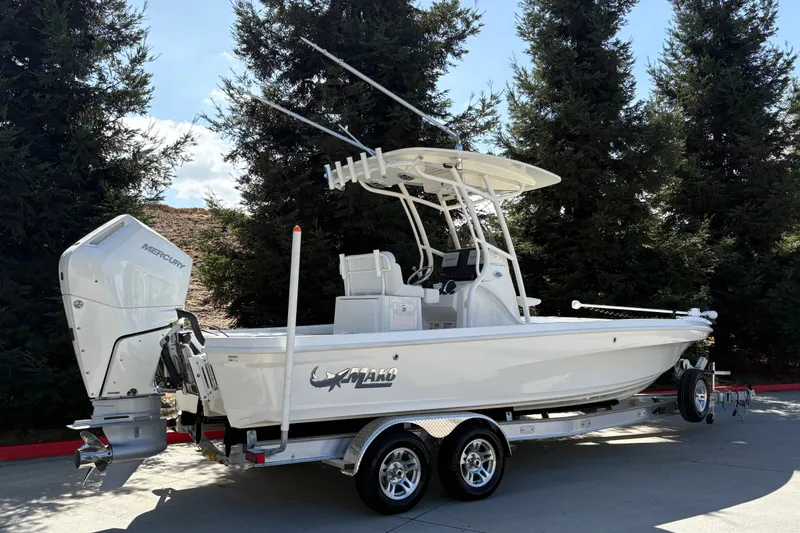 Slide: The Image of 2026 Mako 24 APEX boat on trailer, featuring Mercury outboard motor, parked outdoors. - 2