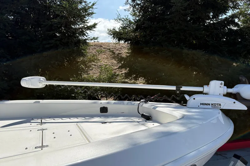 Slide: The Image of 2026 Mako 24 APEX boat with Minn Kota Terrova trolling motor, surrounded by trees. - 11
