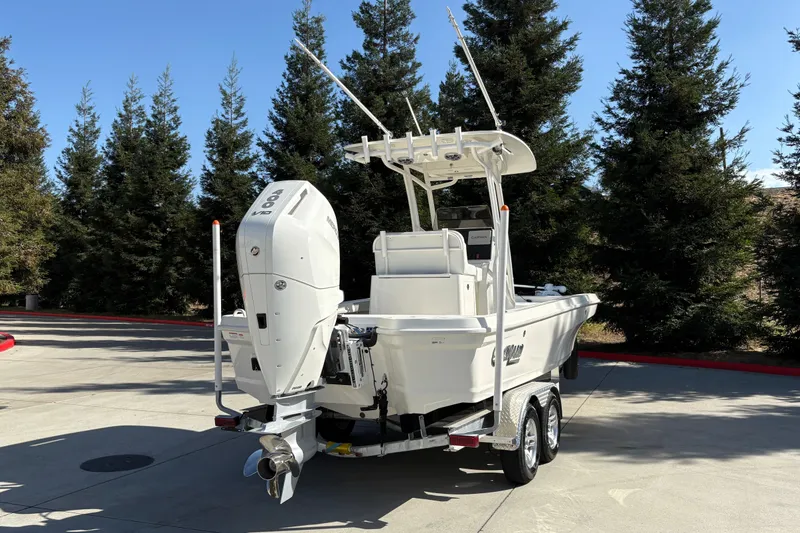 Slide: The Image of 2026 Mako 24 APEX boat on trailer, parked outdoors with trees in background. - 5