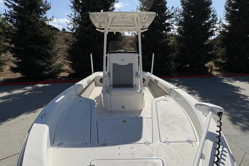 Slide: The Image of 2026 Mako 24 APEX boat with center console and T-top, parked outdoors. - 28