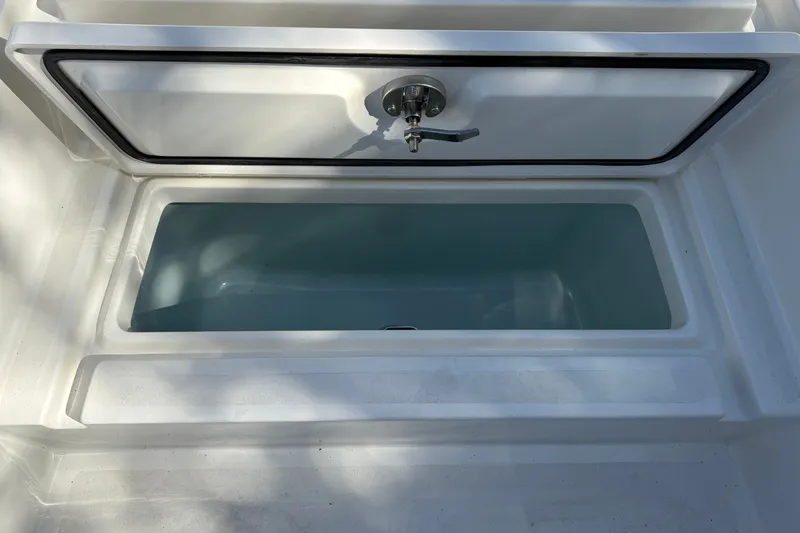Slide: The Image of Open storage compartment on 2026 Mako 24 APEX boat, featuring a secure latch. - 37