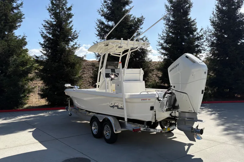 Slide: The Image of 2026 Mako 24 APEX boat with Mercury engine on trailer, parked outdoors. - 8