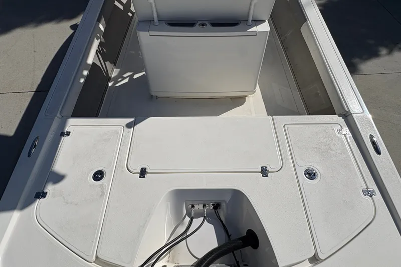 Slide: The Image of Interior view of a 2026 Mako 24 APEX boat, showcasing storage compartments and seating area. - 19
