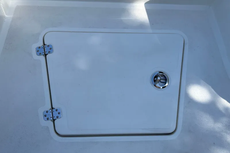 Slide: The Image of Hatch cover on 2026 Mako 24 APEX boat deck, featuring metal hinges and latch. - 30
