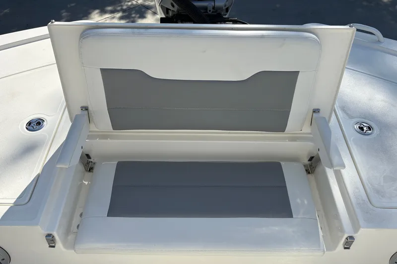 Slide: The Image of 2026 Mako 24 APEX boat seat with gray and white upholstery, open storage compartment. - 23