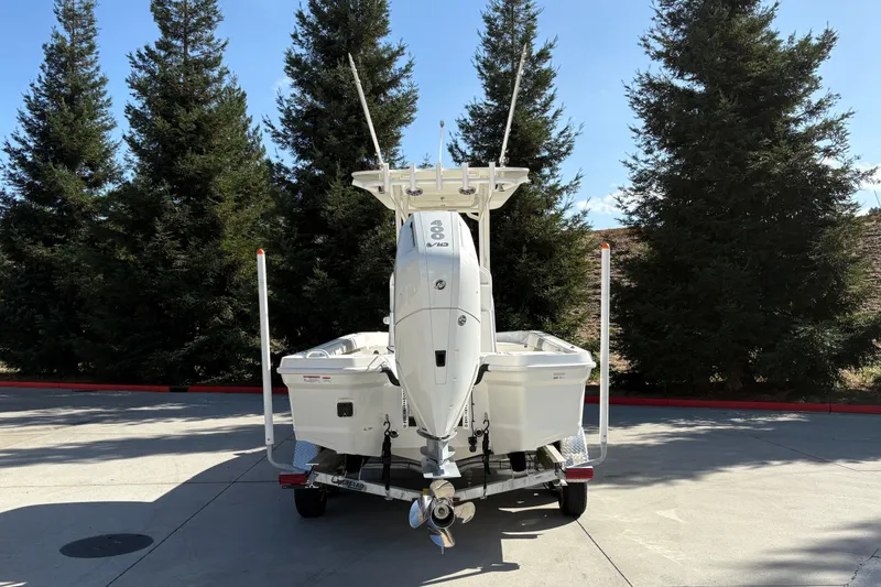 Slide: The Image of 2026 Mako 24 APEX boat on trailer, parked near tall trees. - 10