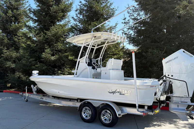 Slide: The Image of 2026 Mako 24 APEX boat on trailer, surrounded by trees, featuring Mercury engine. - 6