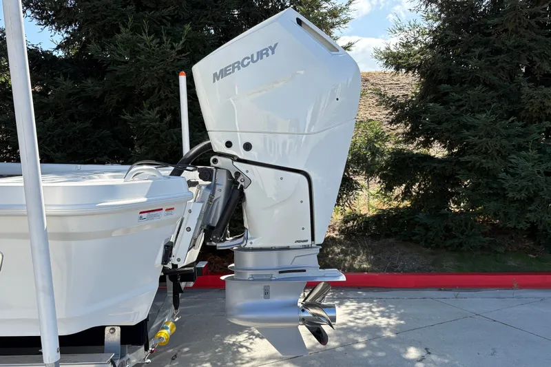 Slide: The Image of 2026 Mako 24 APEX boat with Mercury outboard motor, parked outdoors. - 7