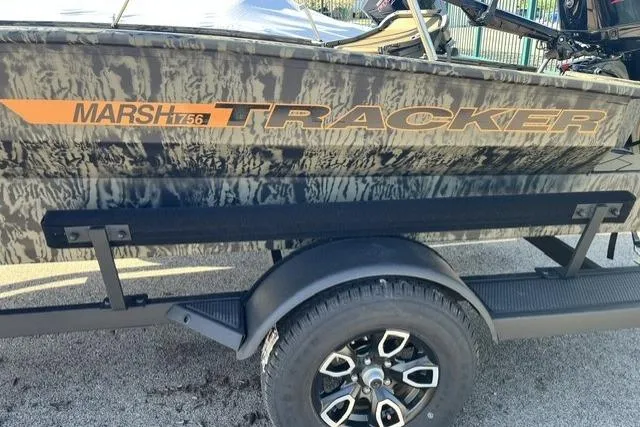 The Image of 2026 Tracker Grizzly 1756 T Marsh boat on trailer, featuring camo design and bold branding. - 0