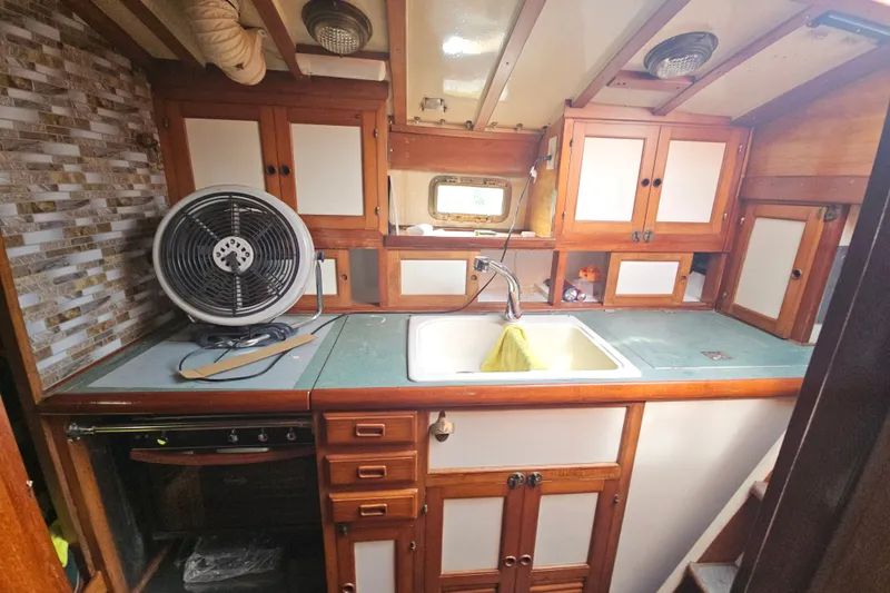 Slide: The Image of 1982 Kadey-Krogen 38 yacht kitchen with wooden cabinets, sink, and countertop fan. - 8