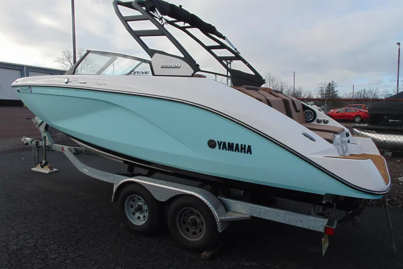Slide: The Image of 2024 Yamaha Boats 222SD on trailer, sleek design, light blue hull, parked outdoors. - 3