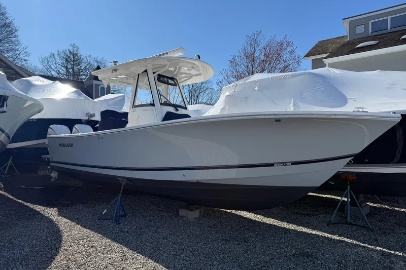 The Image of 2023 Regulator 28 boat on stands, outdoor storage, clear sky background. - 0