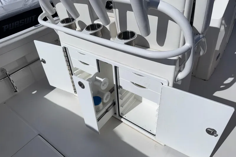 Slide: The Image of 2023 Regulator 28 boat storage compartments with open doors and rod holders. - 10
